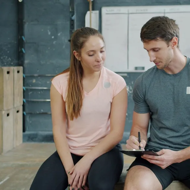 A personal trainer reviewing notes with a member